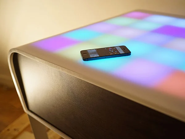 TA+BLE, a coffee table with multicoloured illuminated cells and an iPhone on top.